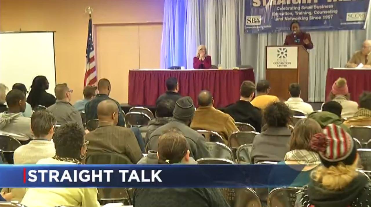 A group of people are sitting in front of a podium that says straight talk