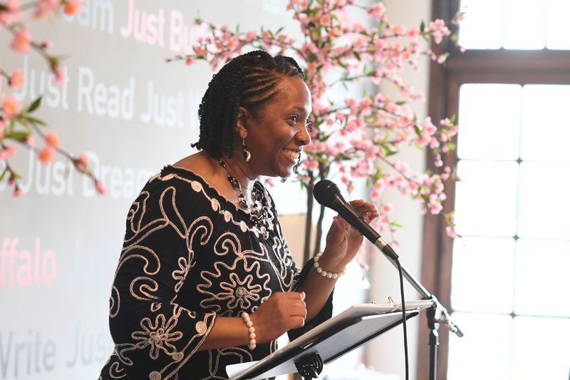 A woman is standing at a podium speaking into a microphone.