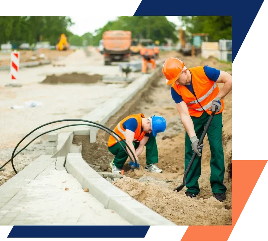 Two construction workers are working on a road