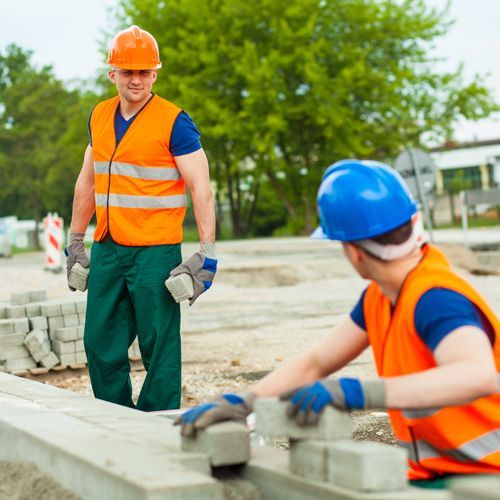 Two construction workers wearing orange vests and hard hats