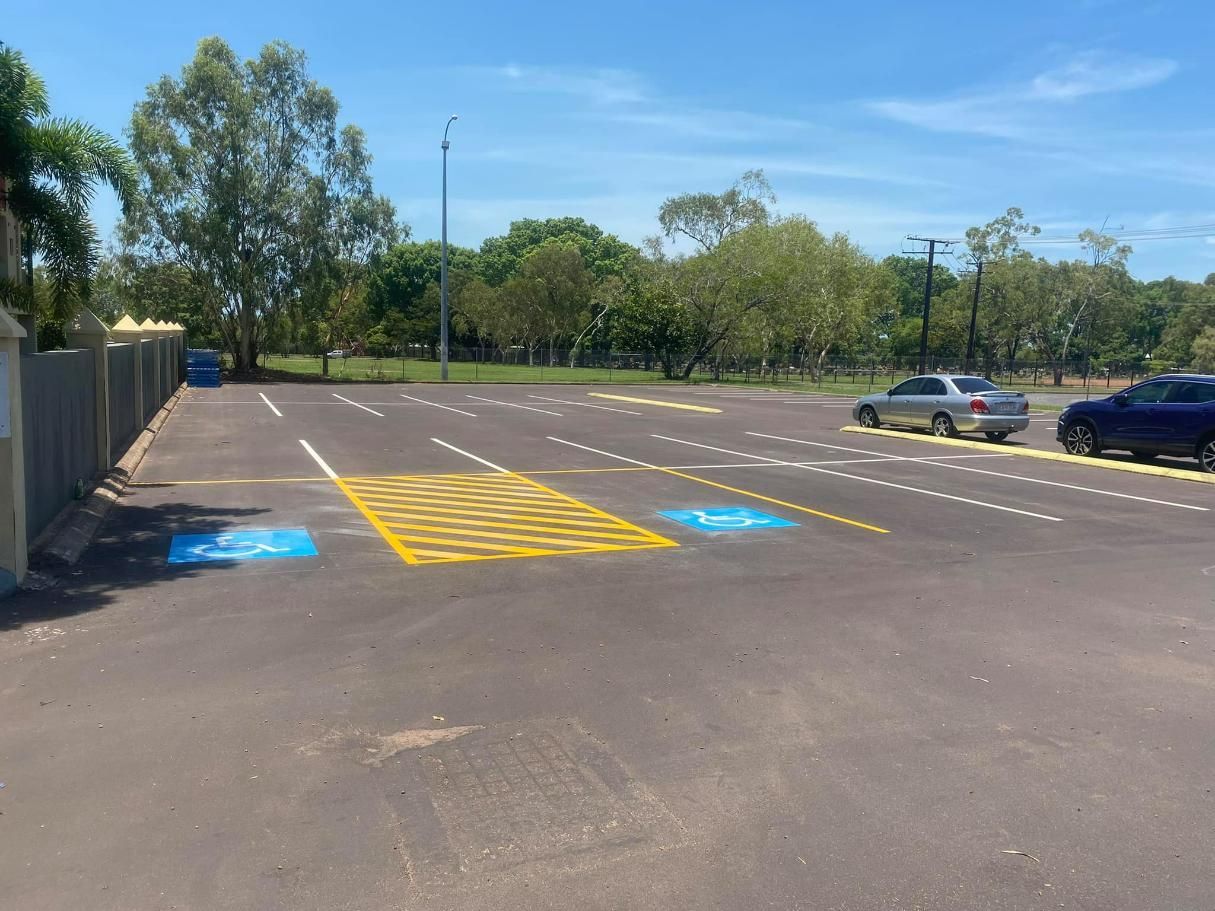 A Parking Lot with A Handicapped Sign Painted on The Side of The Road — Top End Line Markers Pty Ltd in Katherine, NT