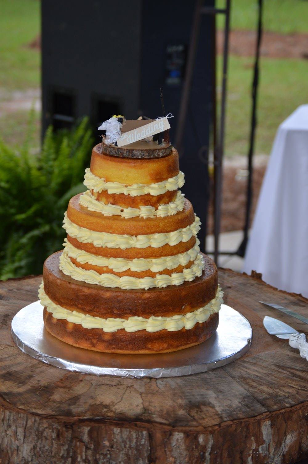 A wedding cake is sitting on top of a wooden stump.