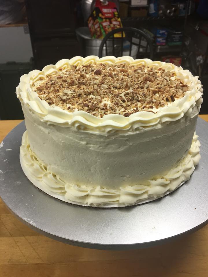 A cake with frosting and nuts on top is sitting on a metal plate.