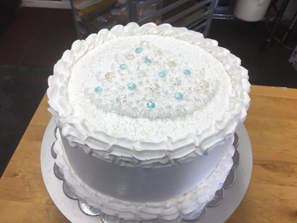A white cake with white frosting and blue sprinkles on top