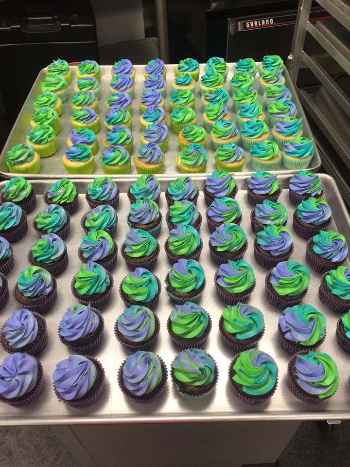 A tray of cupcakes with blue and green frosting