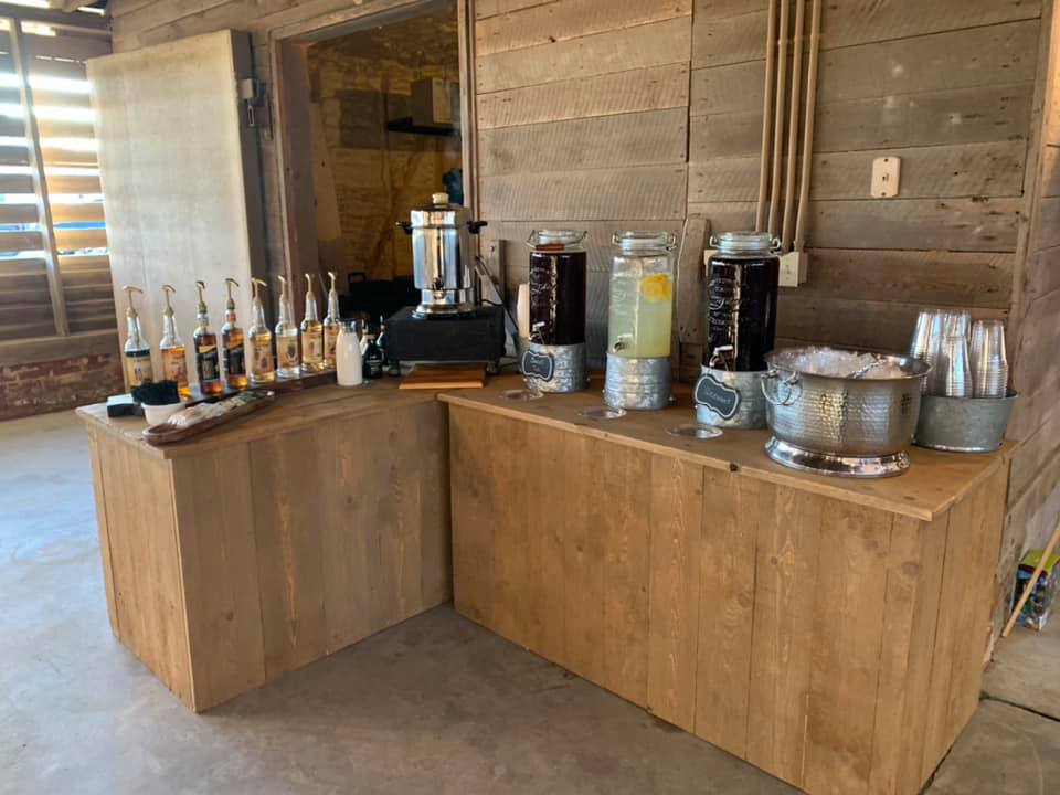 A wooden table with bottles of liquor and drink dispensers on it.