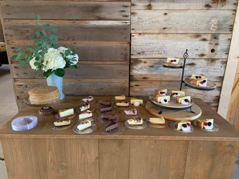 A wooden table topped with a variety of desserts and flowers.