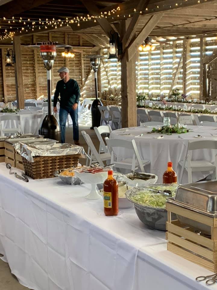 A man is standing in front of a buffet table in a barn.