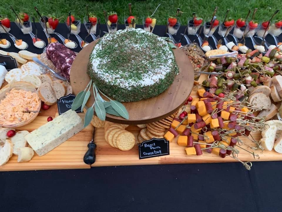 A buffet table with a cake on top of a wooden cutting board.