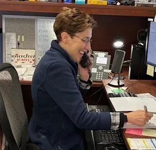 A woman is sitting at a desk talking on a phone