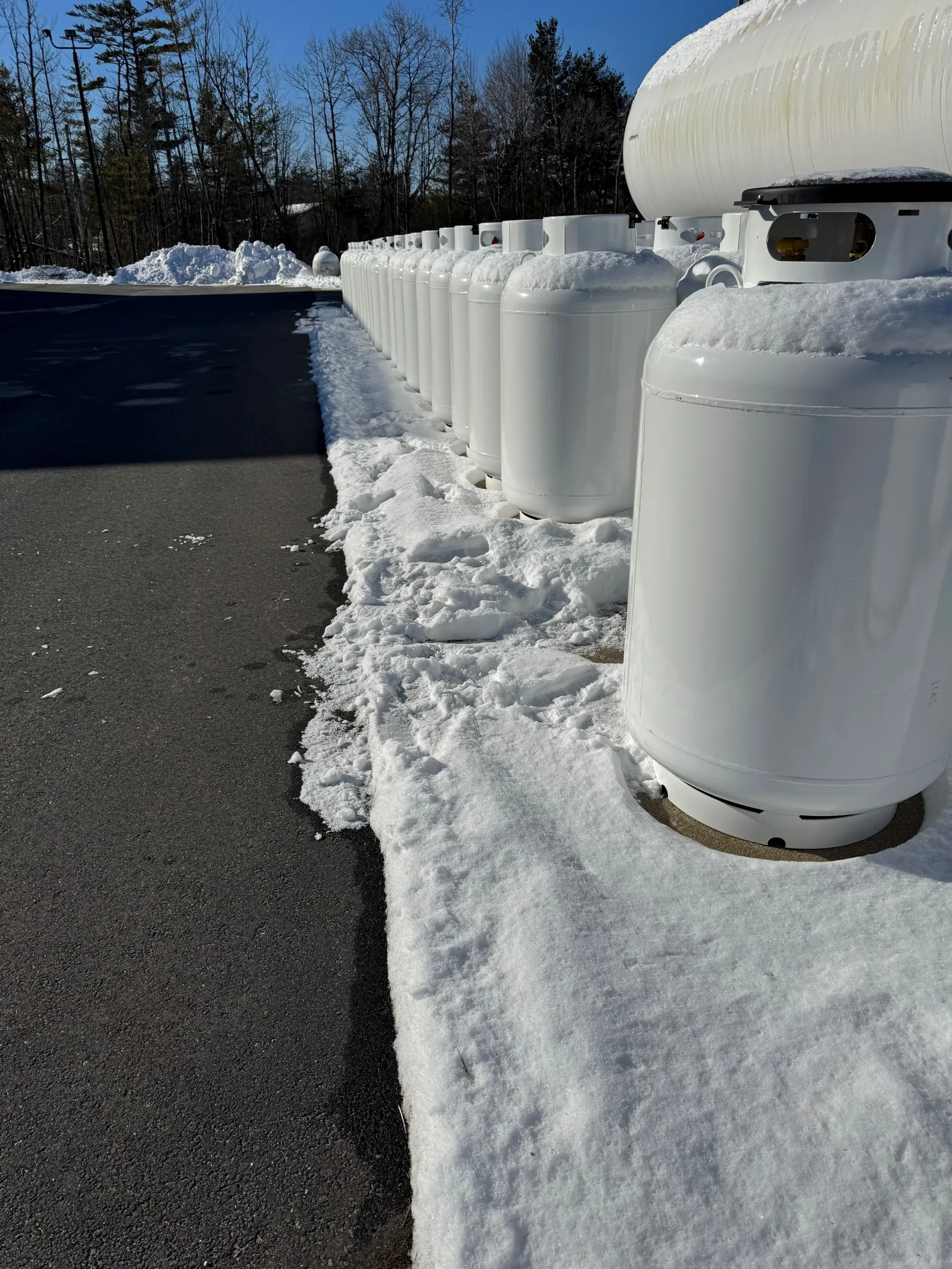 A row of white propane tanks are lined up in a row.