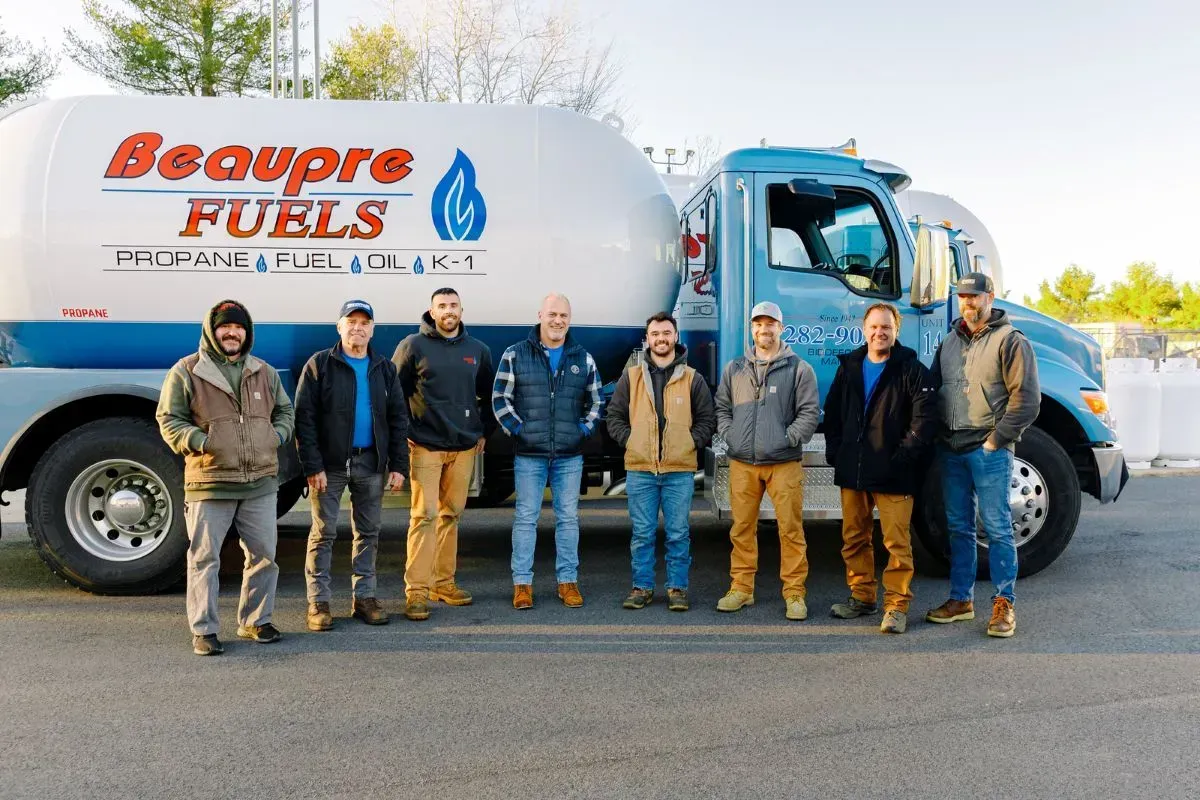 A group of men standing in front of a beaupre fuels truck