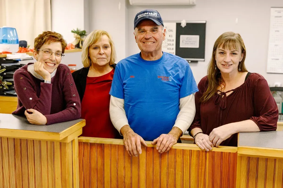 A group of people are posing for a picture in front of a wooden counter.