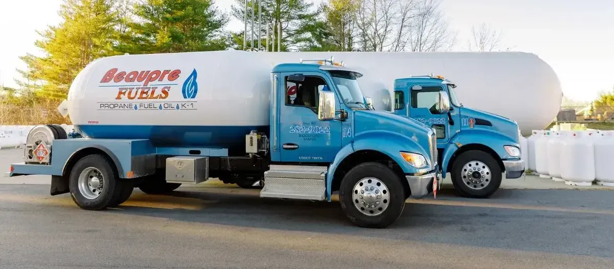 Two propane trucks are parked next to each other on the side of the road.