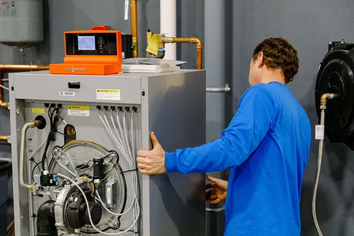 A man in a blue shirt is working on a heating system.