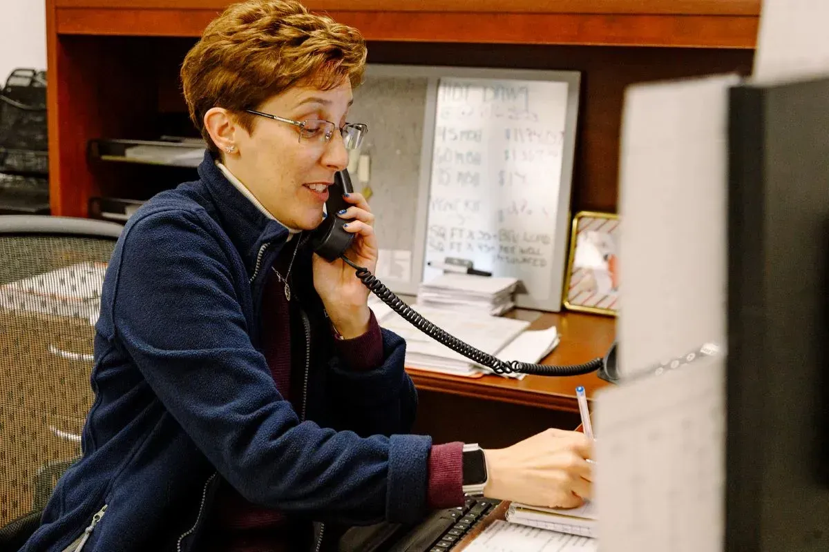 A woman is sitting at a desk talking on a phone