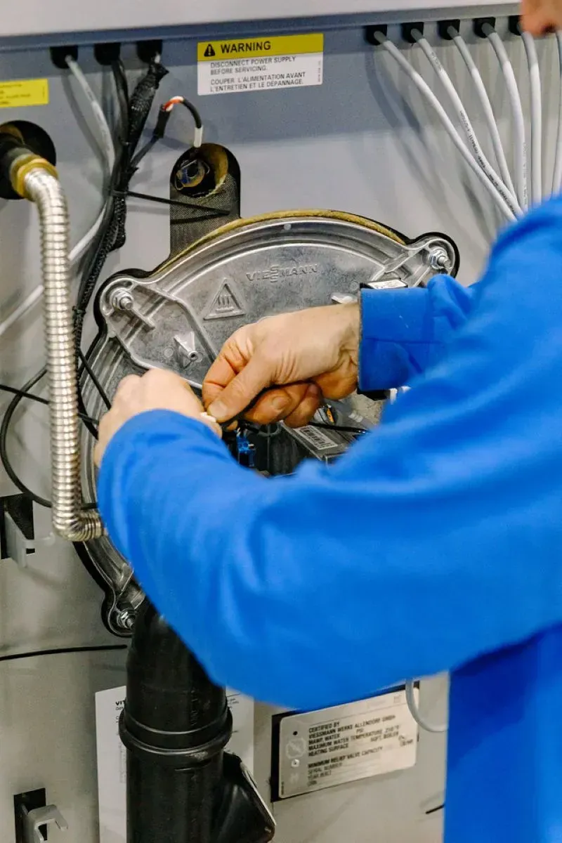 A man in a blue jacket is working on a machine.