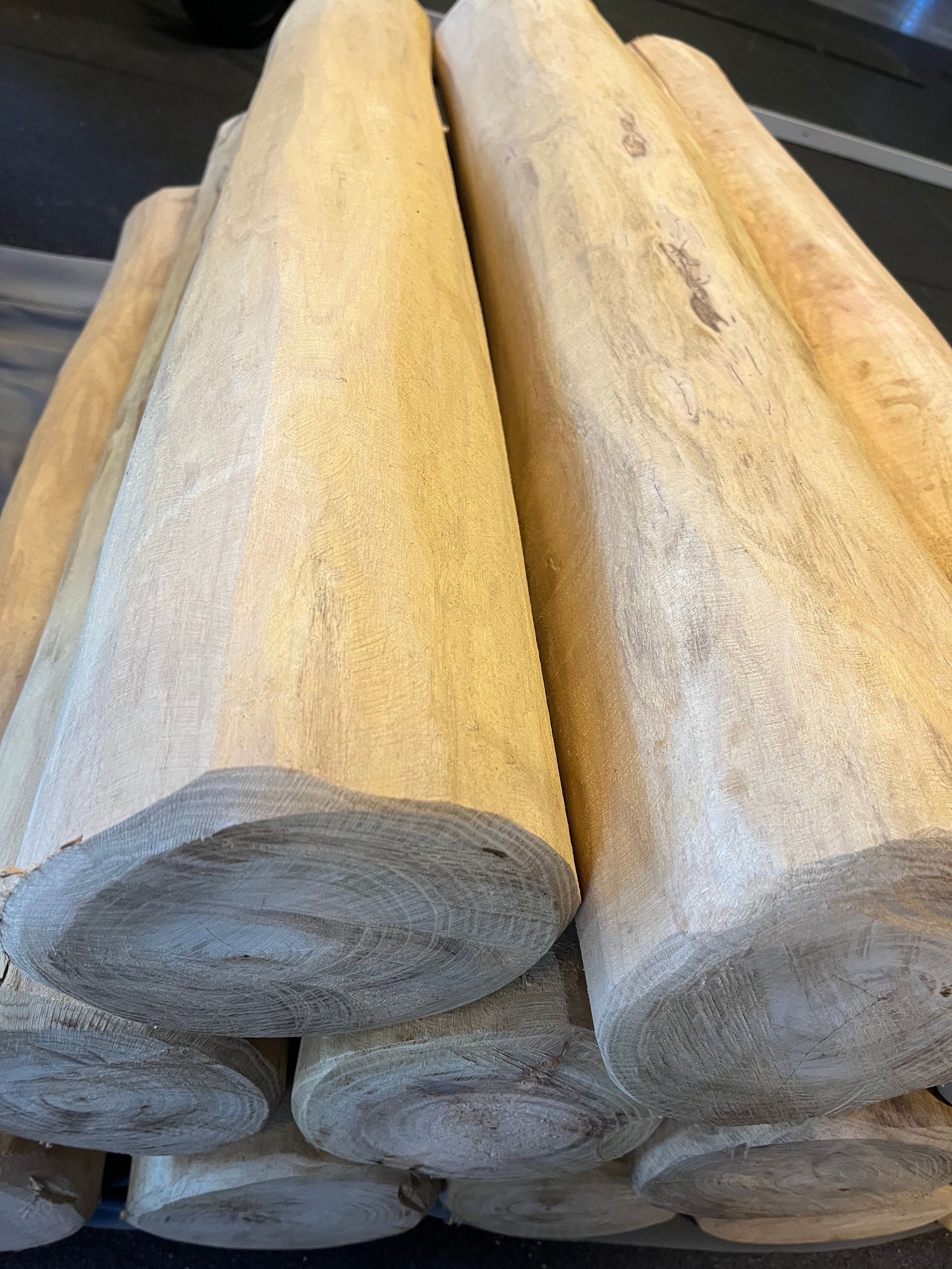 Opgestapelde boomstammen, aan beide uiteinden doorgezaagd, beige van kleur, ruwe textuur.