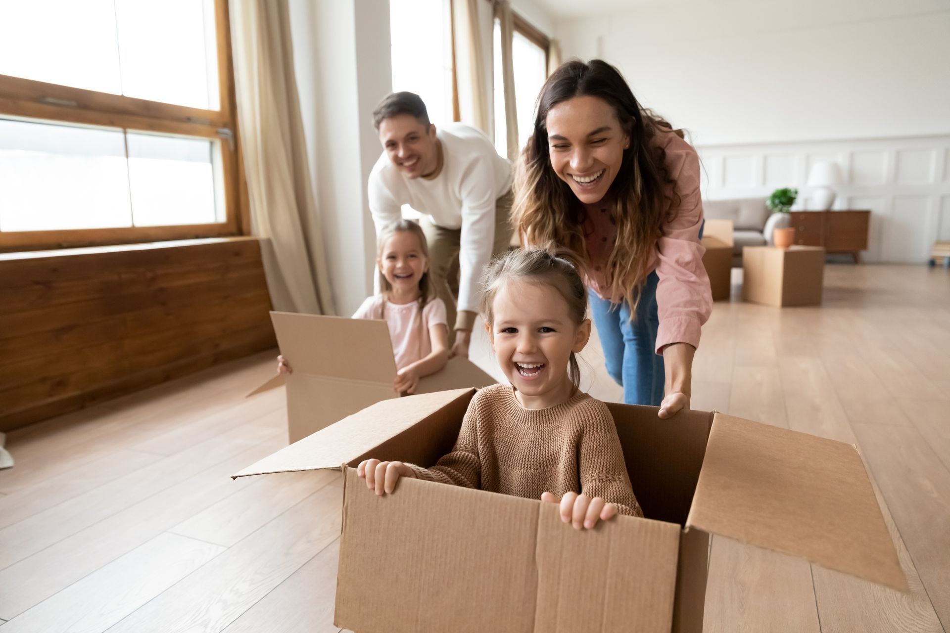 A family is playing in a cardboard box in their new home.