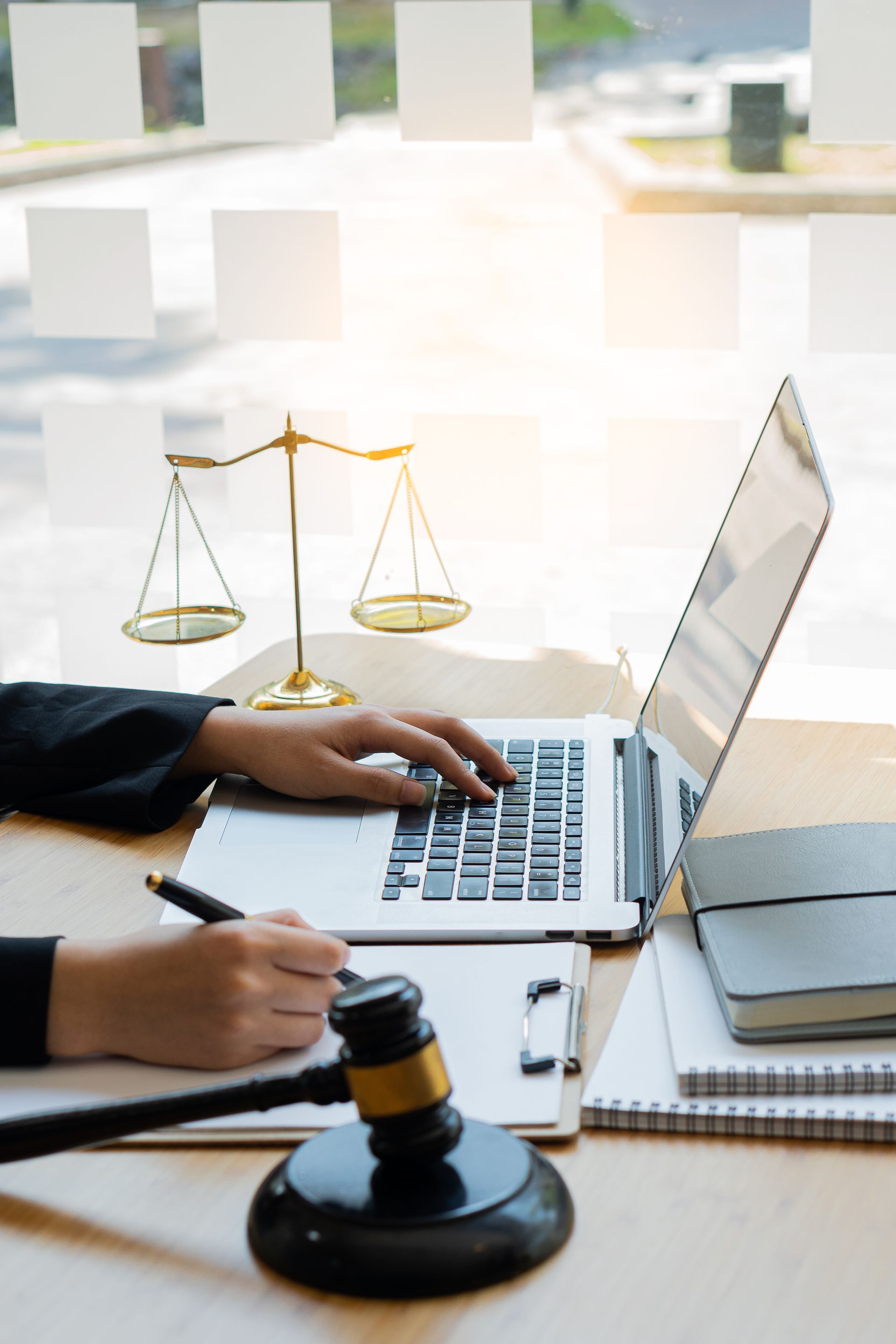 A judge is typing on a laptop computer while holding a gavel.