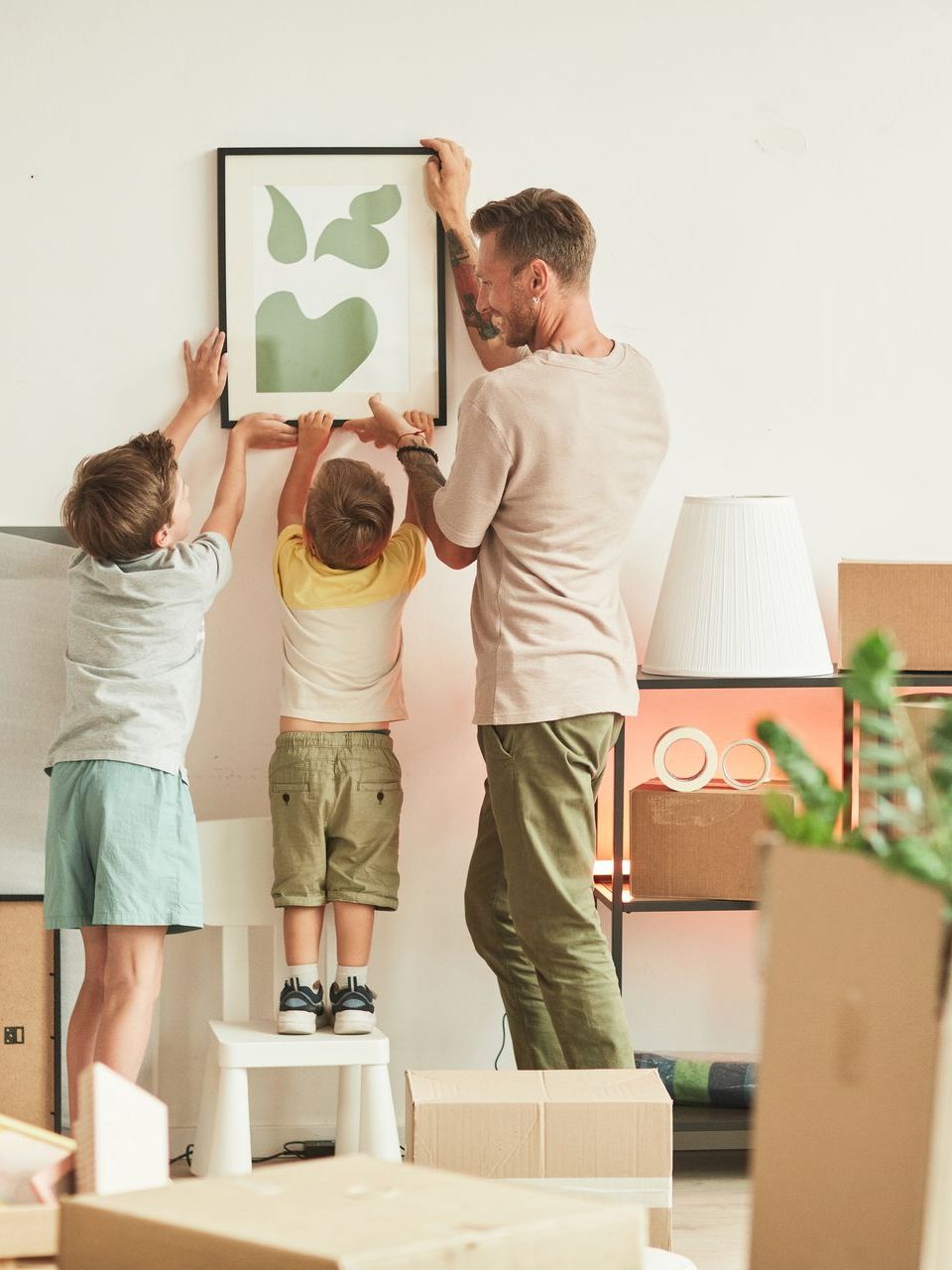 A man and two children are hanging a picture on a wall.