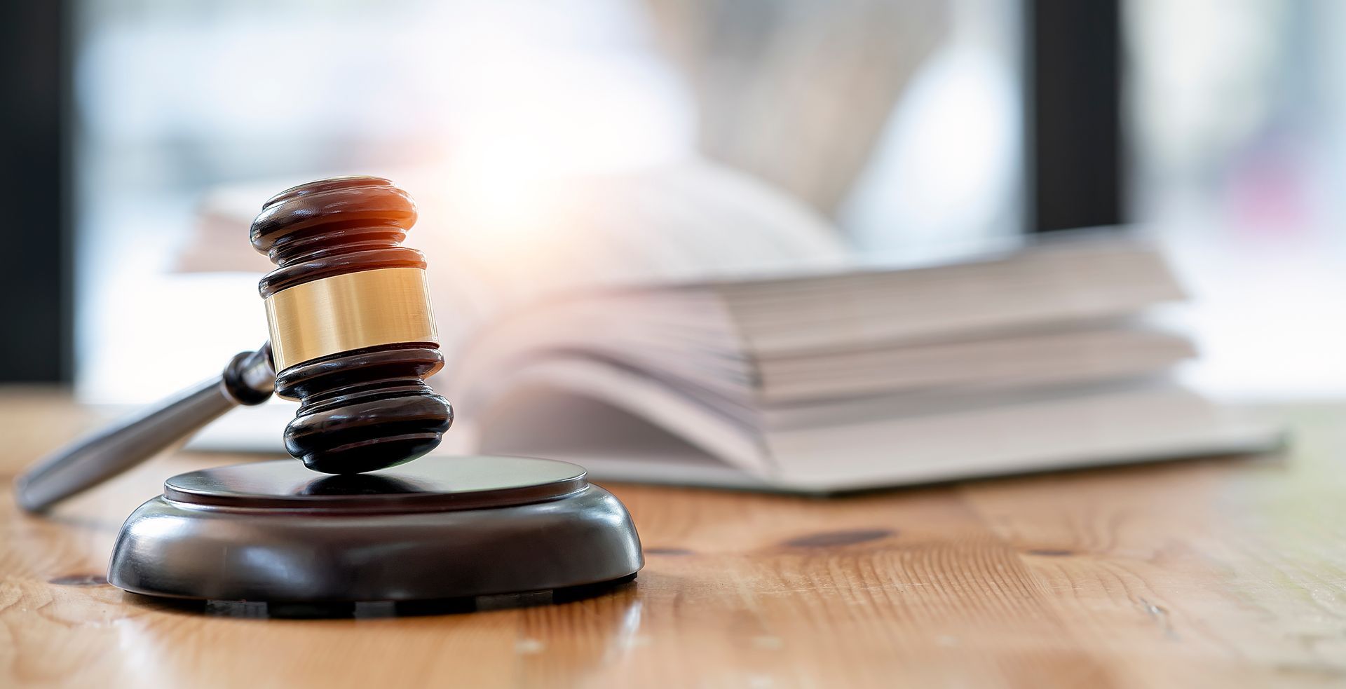 A judge 's gavel is sitting on a wooden table in front of a stack of books.