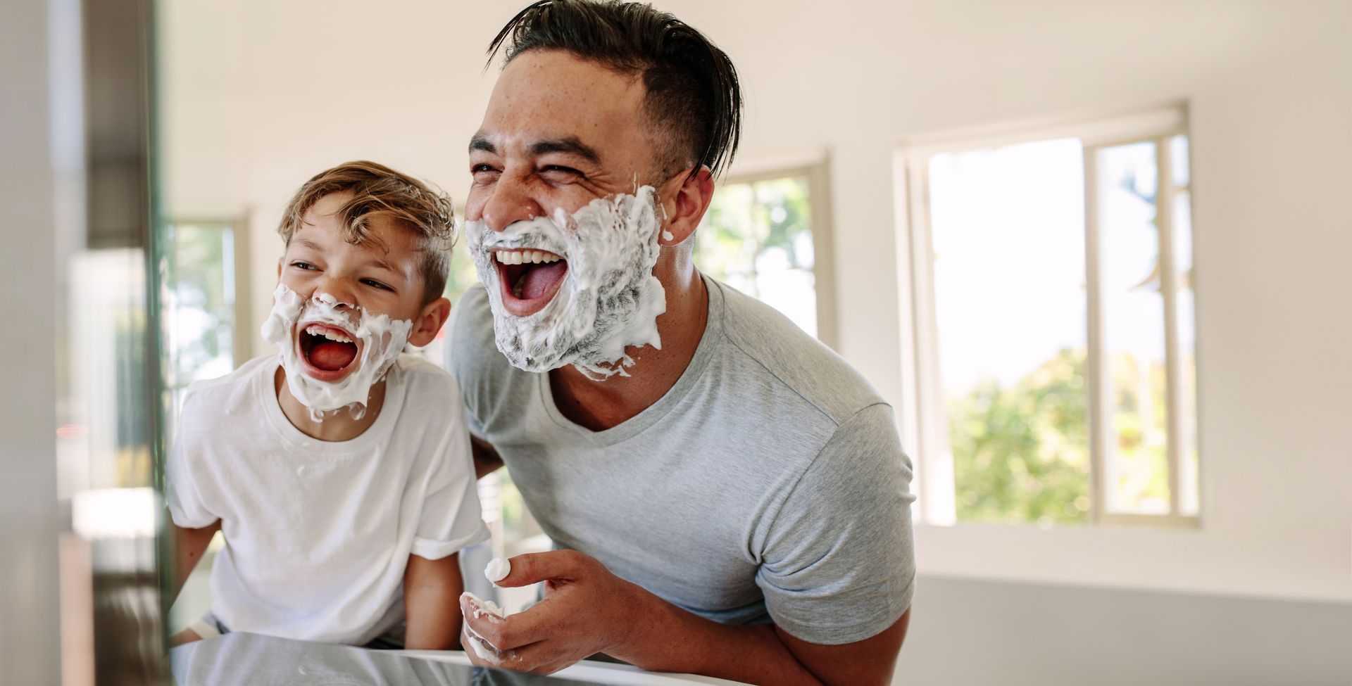 A man and a boy with shaving cream on their faces.