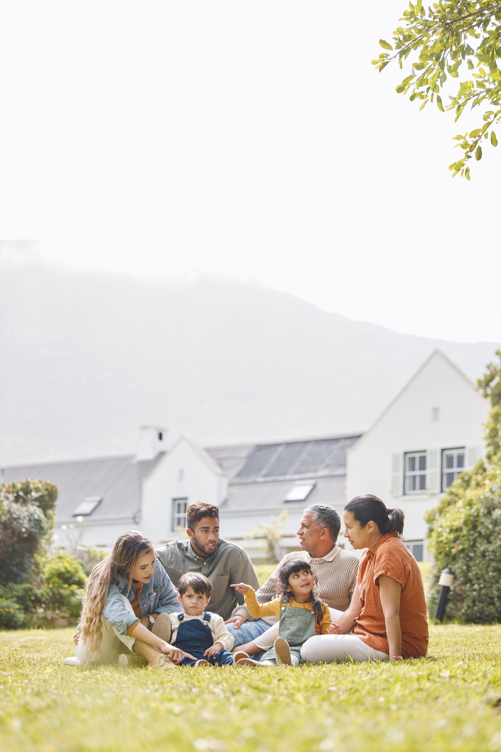 A family is sitting on the grass in a park.