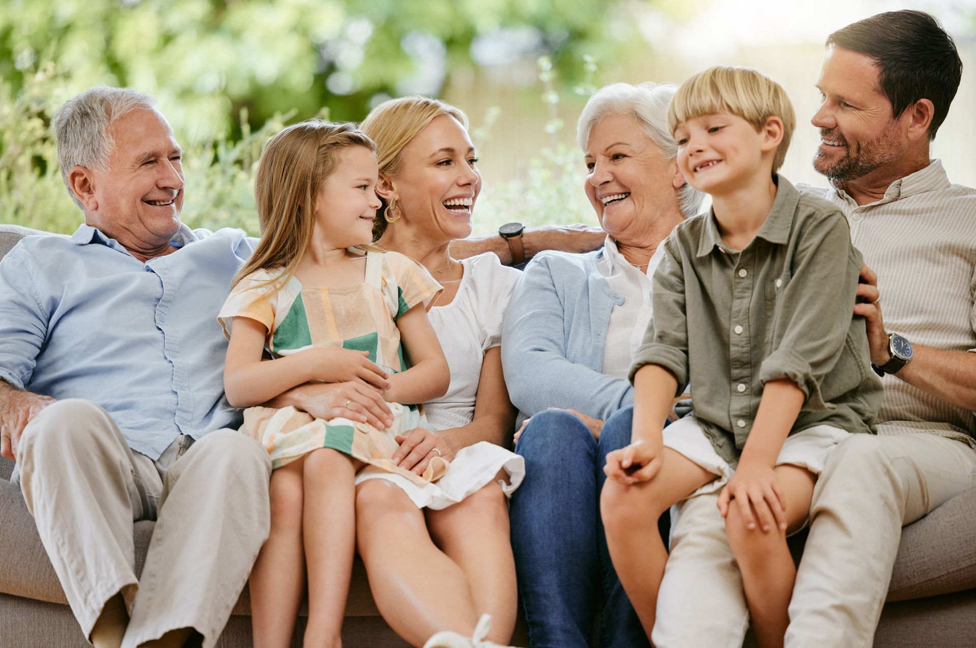 A large family is sitting on a couch together and smiling.