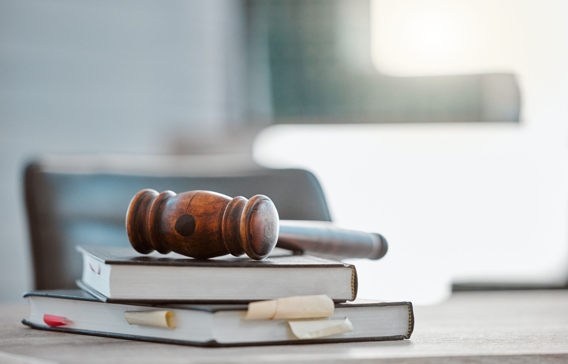 A wooden judge 's gavel is sitting on top of a stack of books.