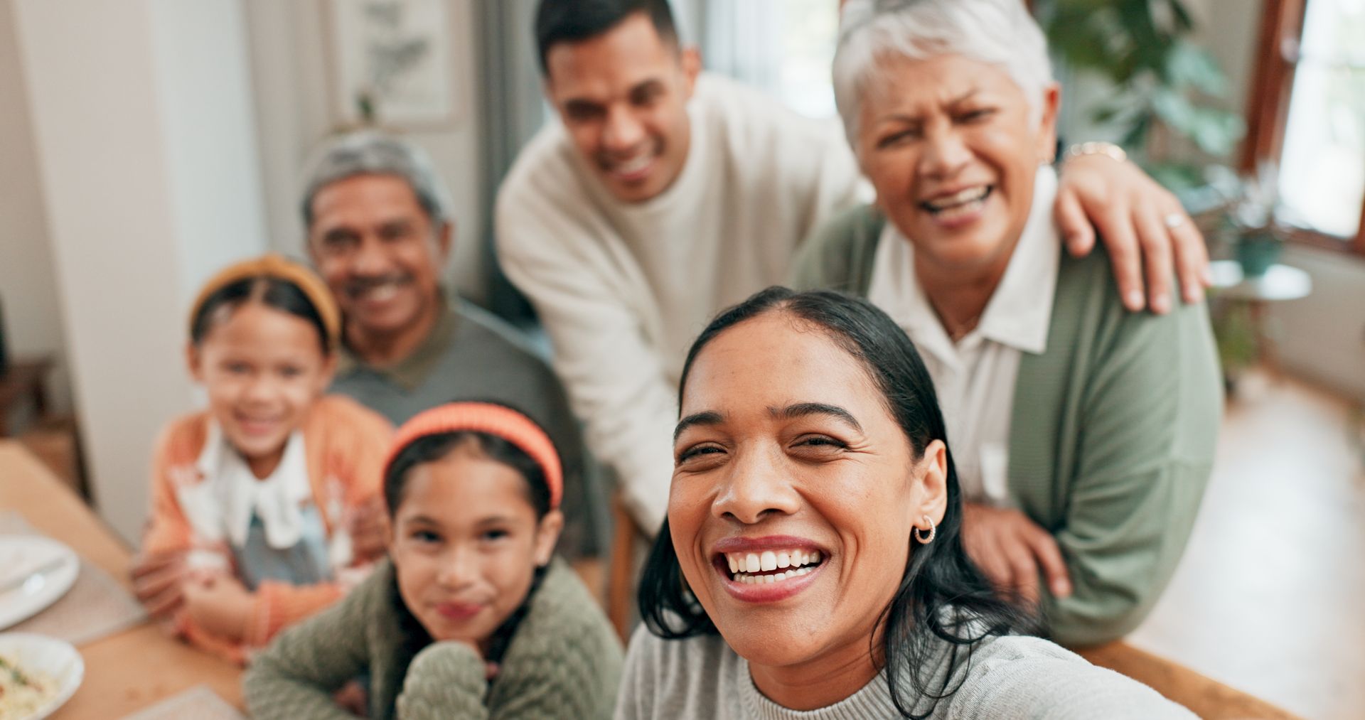 A woman is taking a selfie with her family while sitting at a table.