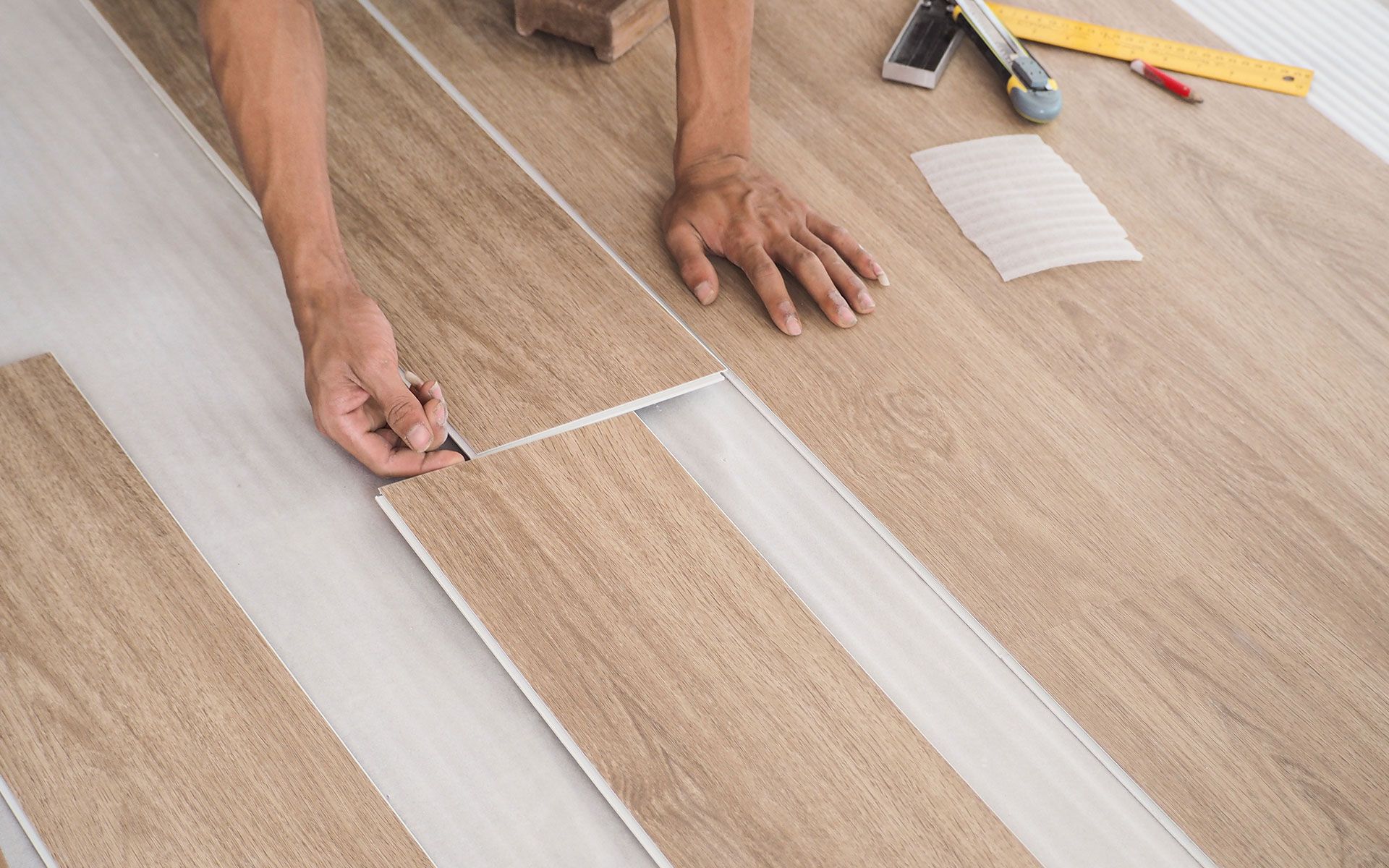 A person is installing a wooden floor in a room.