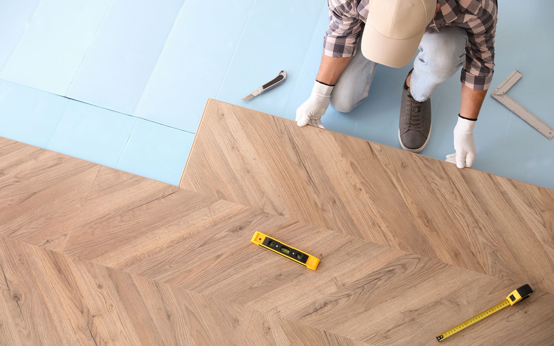 A man is installing a wooden floor in a room.
