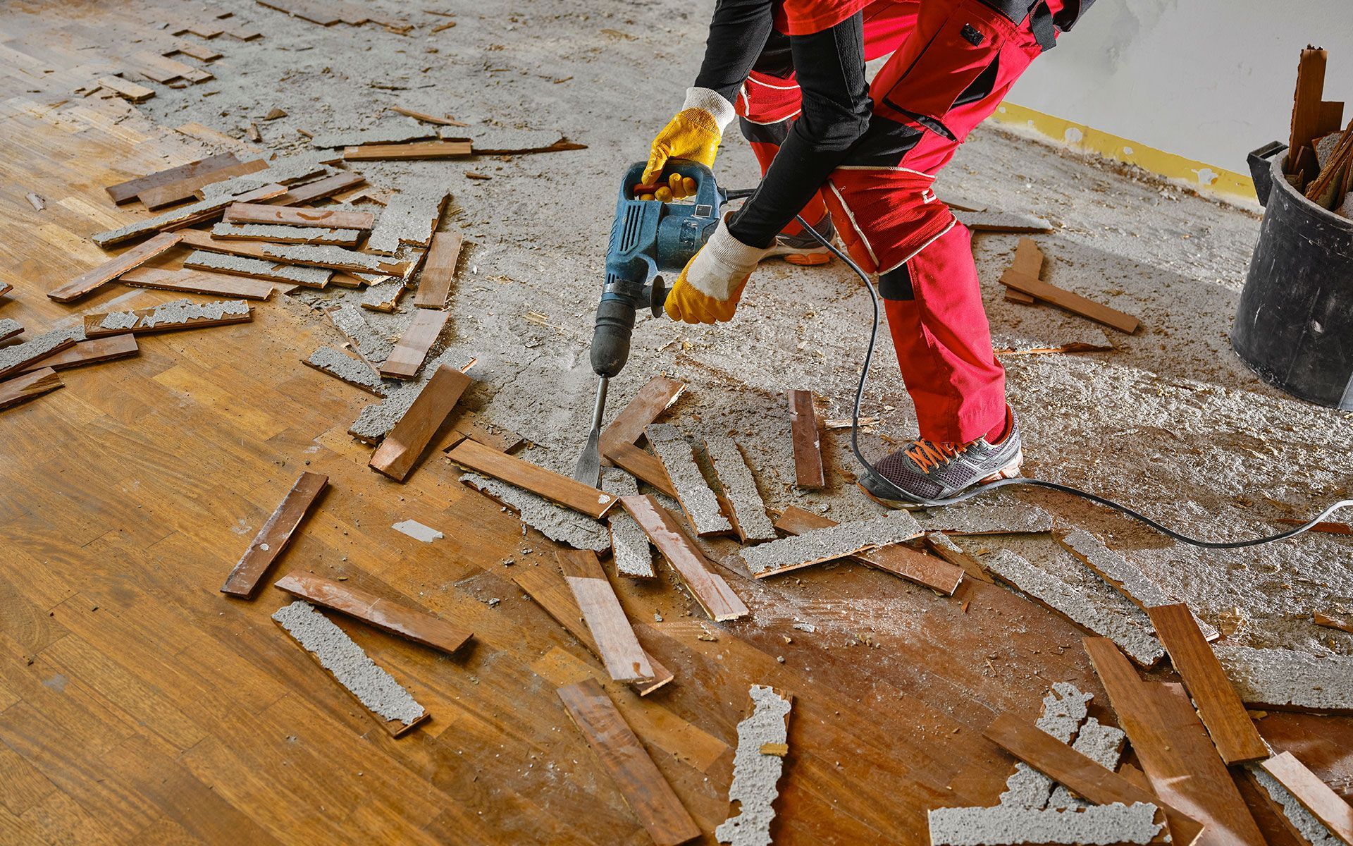 A person is using a hammer to drill a hole in a wooden floor.