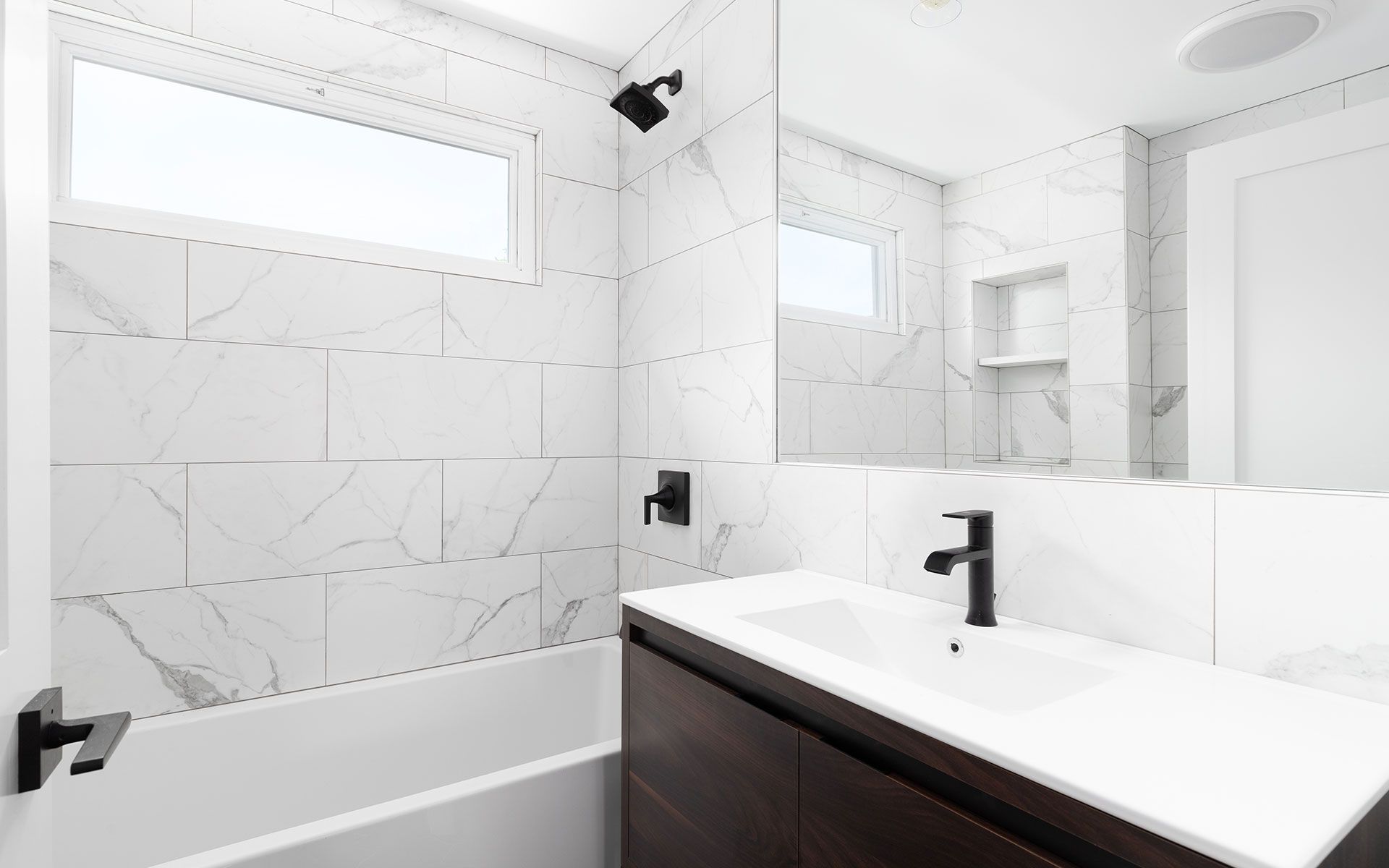 A bathroom with a sink , tub , mirror and window.