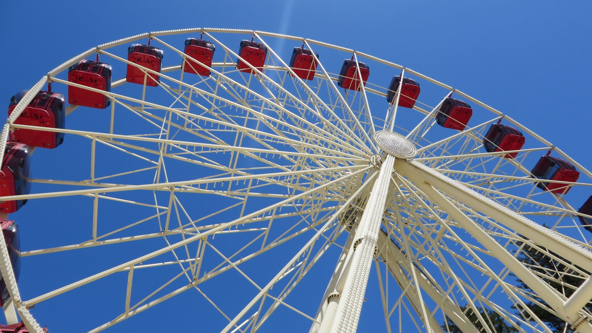Ferris wheel with red gondolas against a clear blue sky.