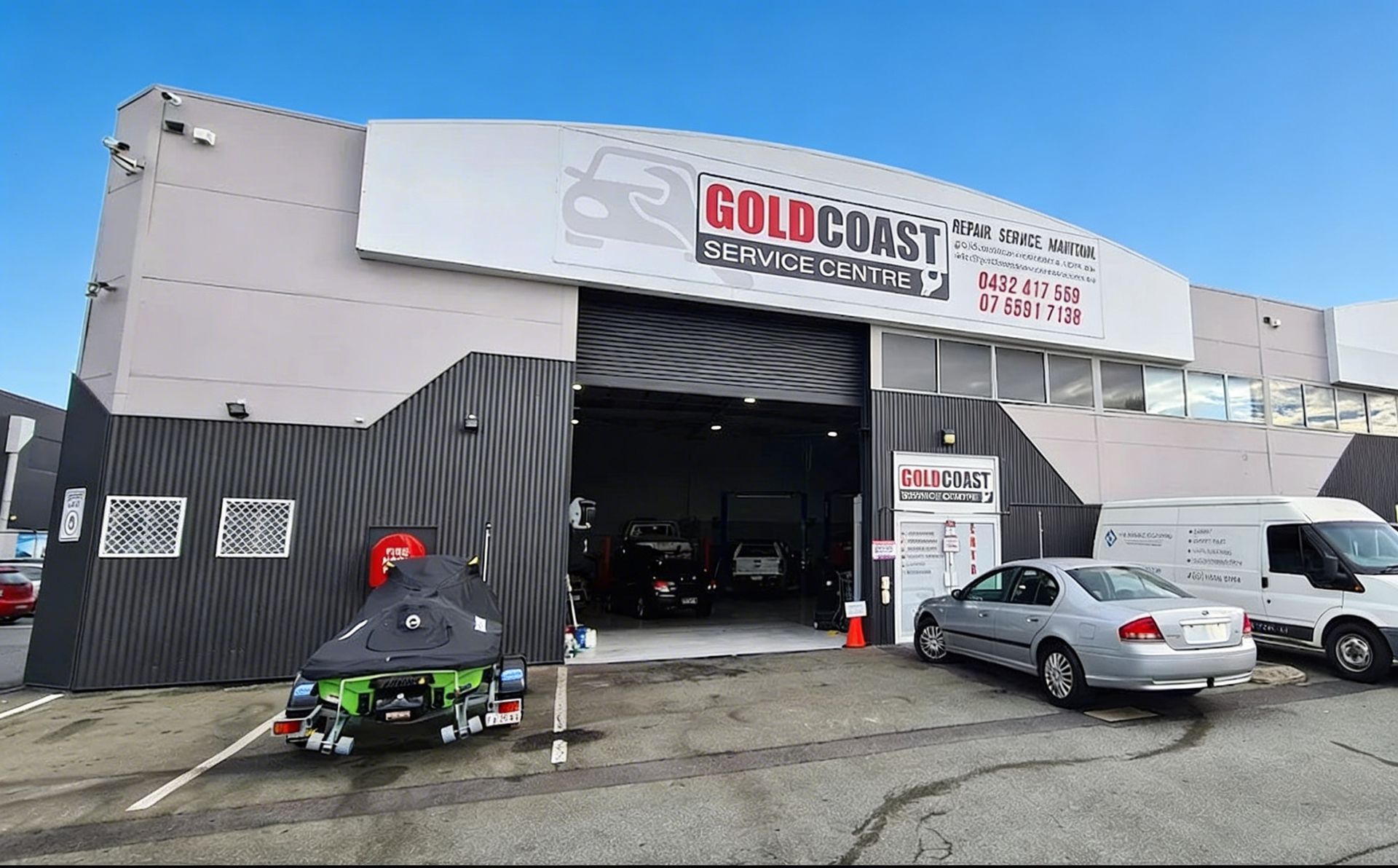 A woman hands car keys to another person in a bright, modern car dealership.