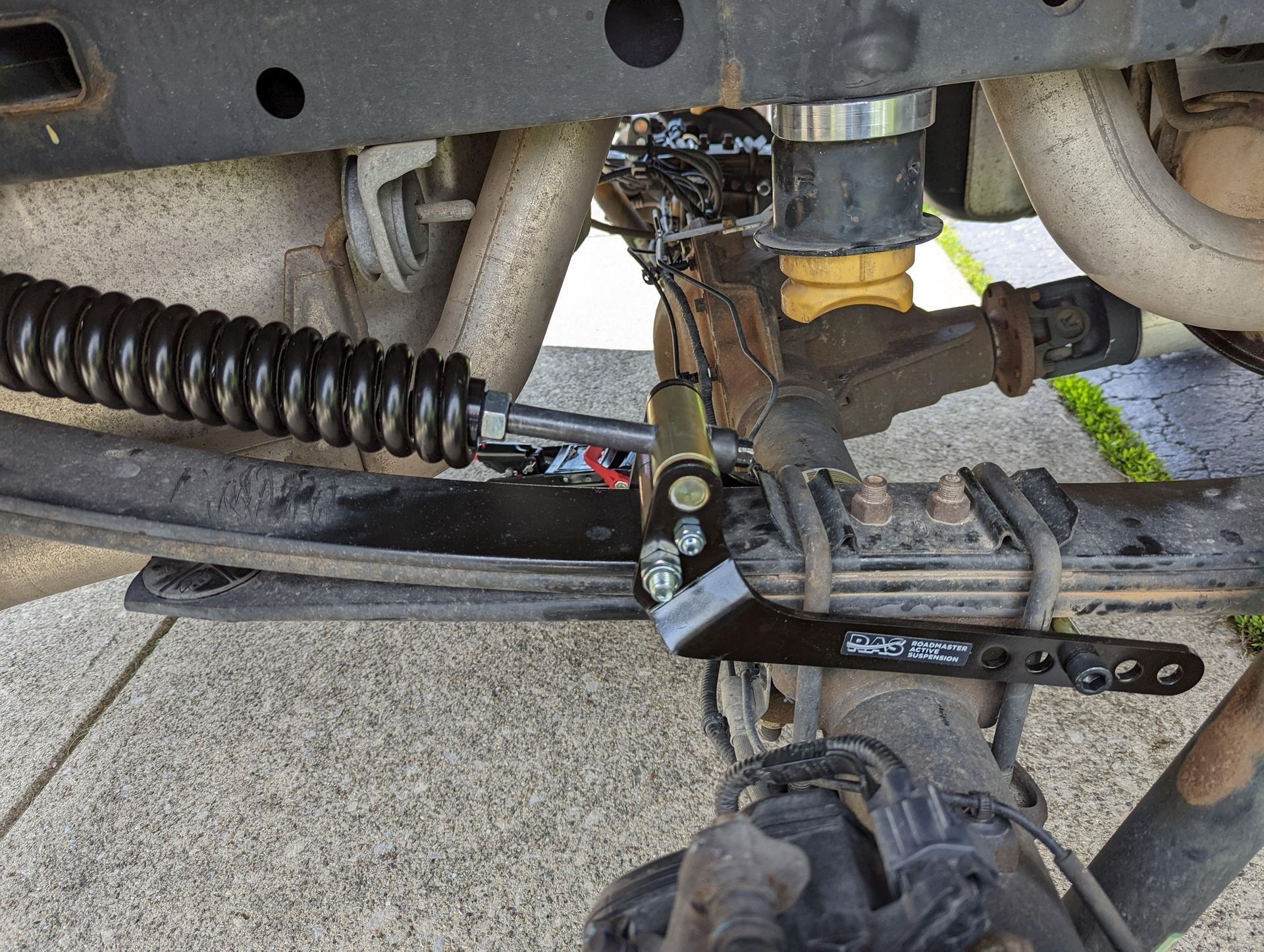 Four smiling people stand with arms crossed in front of a garage workshop, wearing matching navy work shirts.