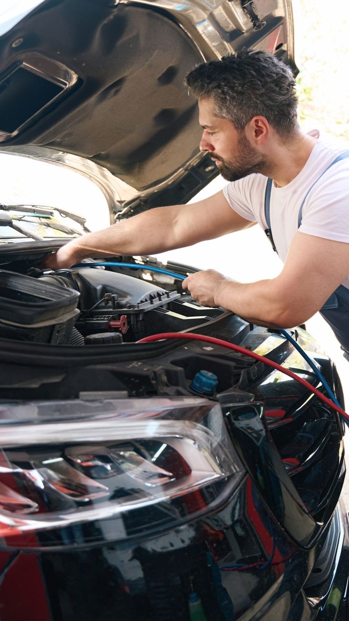 A woman hands car keys to another person in a bright, modern car dealership.