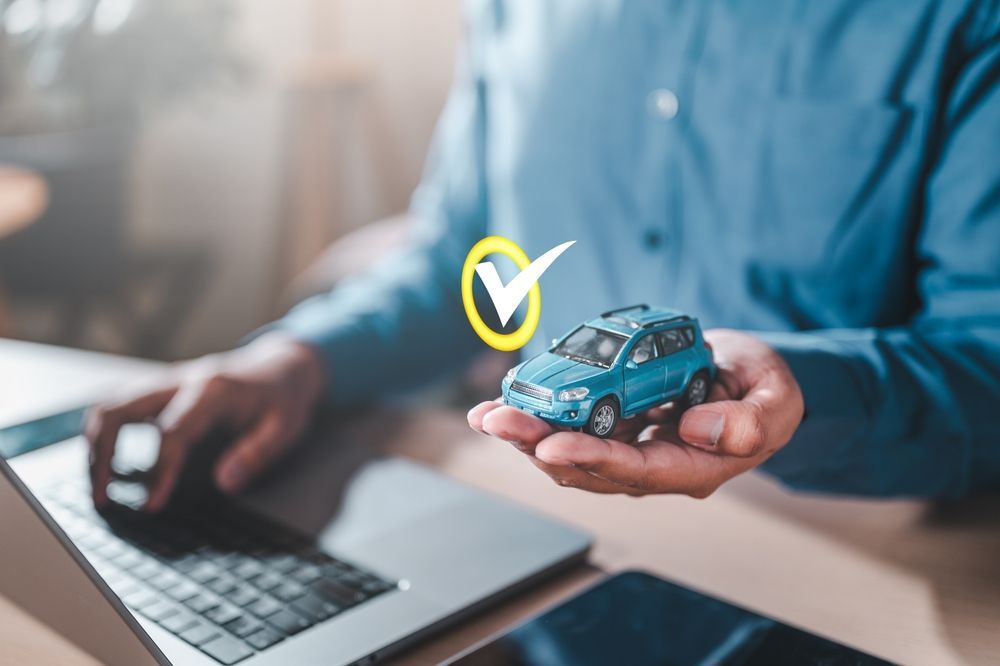 A person writing on a clipboard while inspecting the open engine bay of a car.