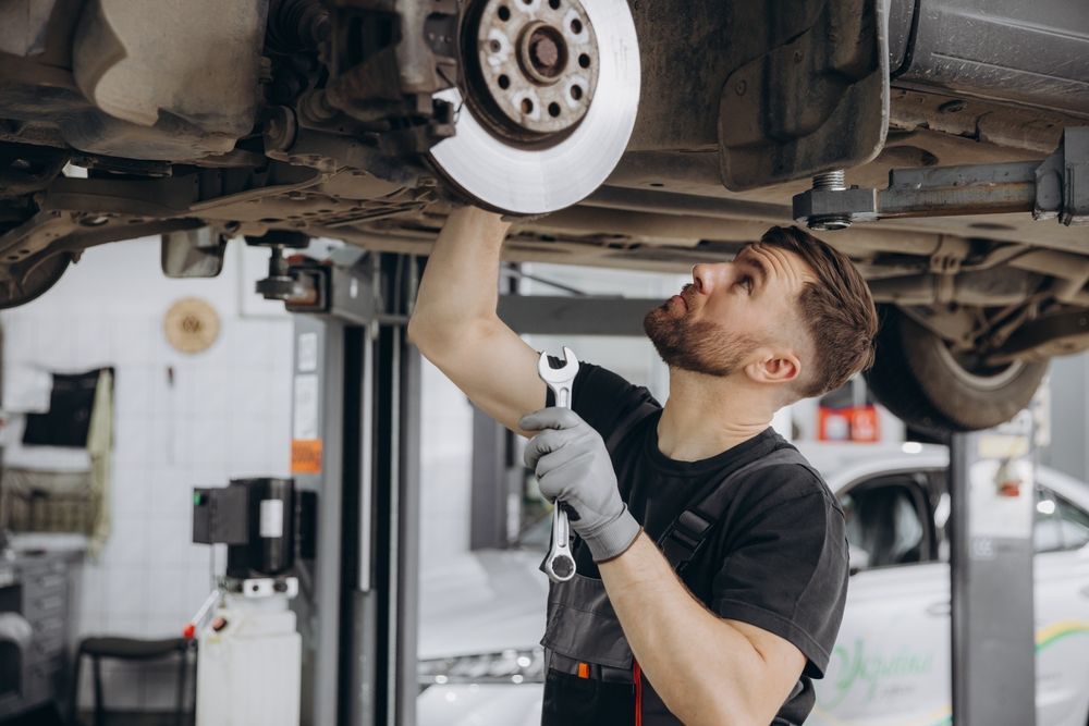 A person writing on a clipboard while inspecting the open engine bay of a car.