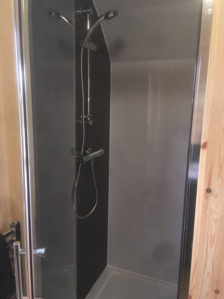 A shower with a glass door and a shower head in a bathroom.