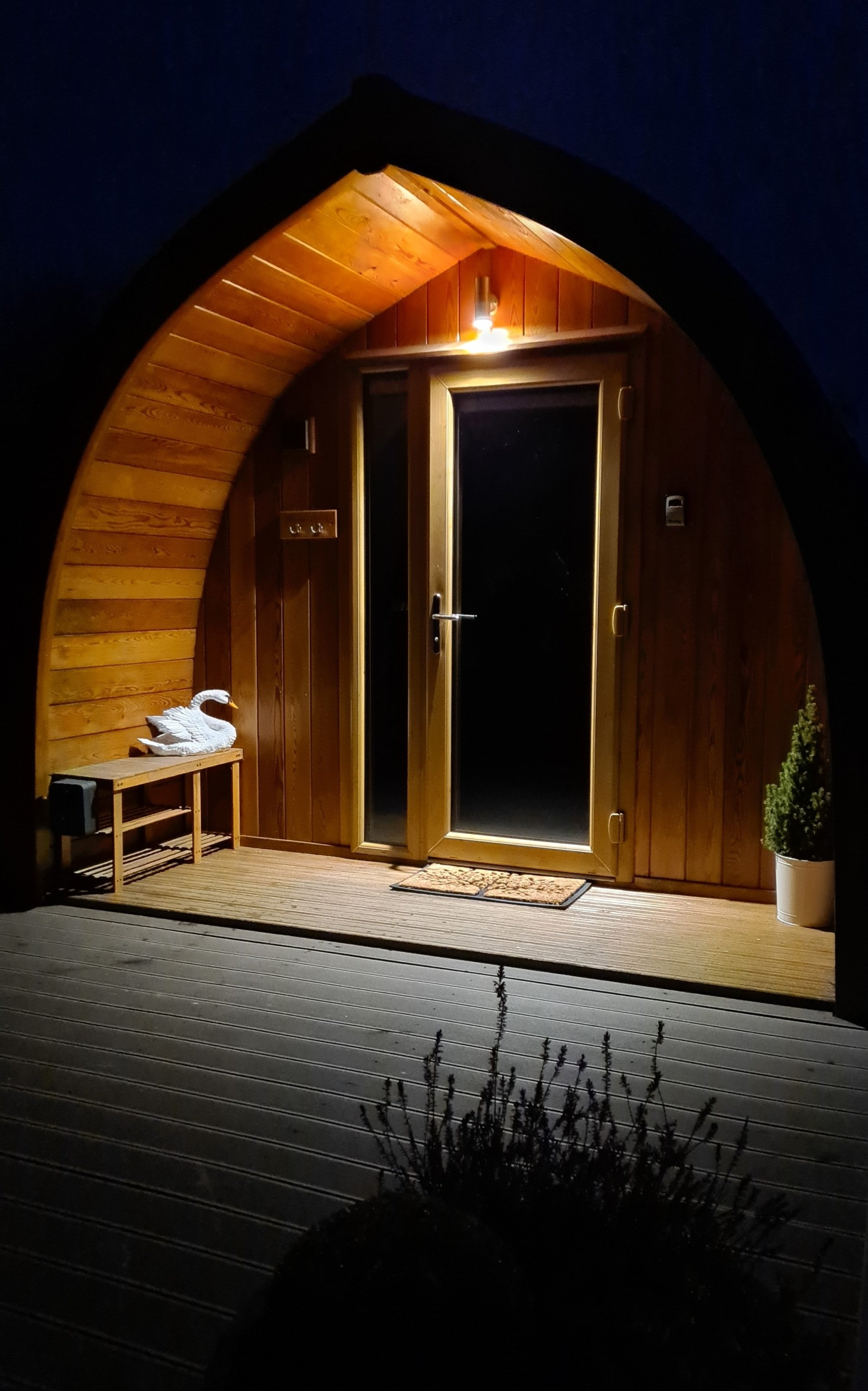 The door of a wooden pod is lit up at night.