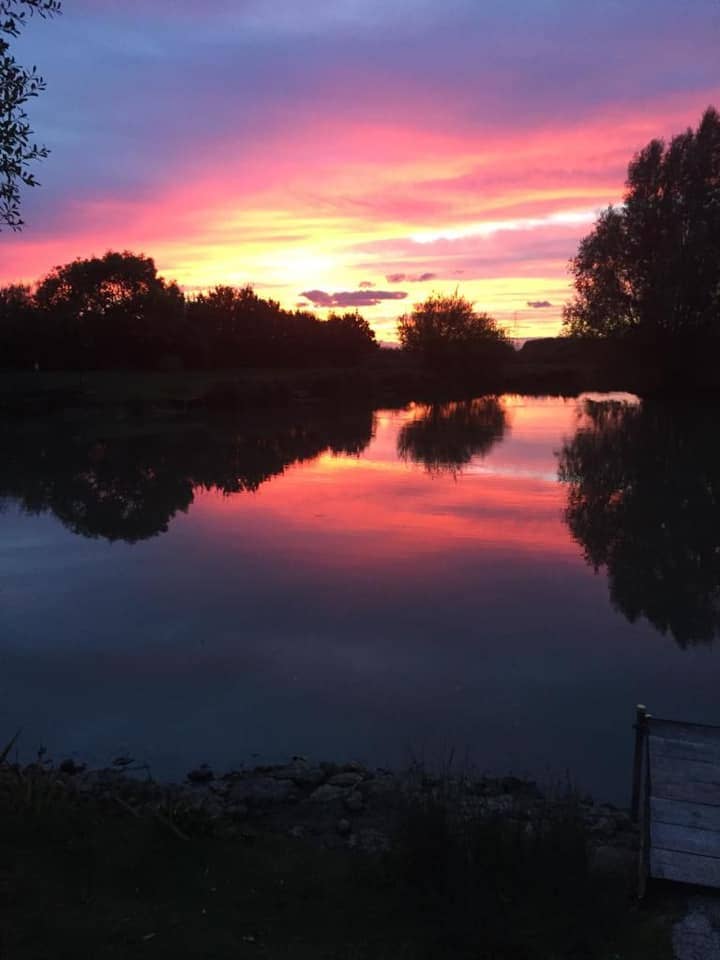 A sunset over a lake with a dock in the foreground