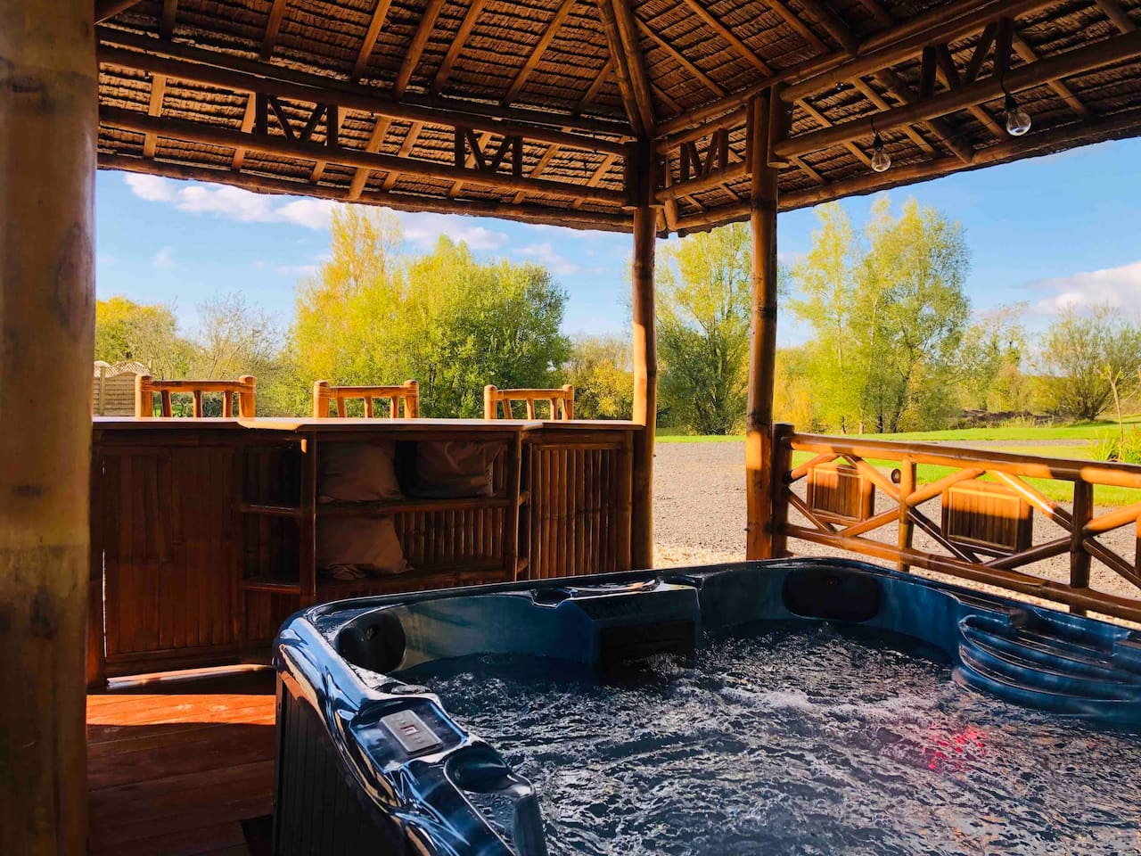 A blue hot tub is sitting under a gazebo.