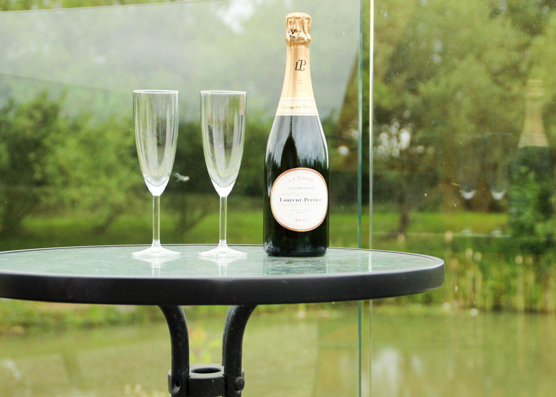 A bottle of champagne and two wine glasses are on a table.