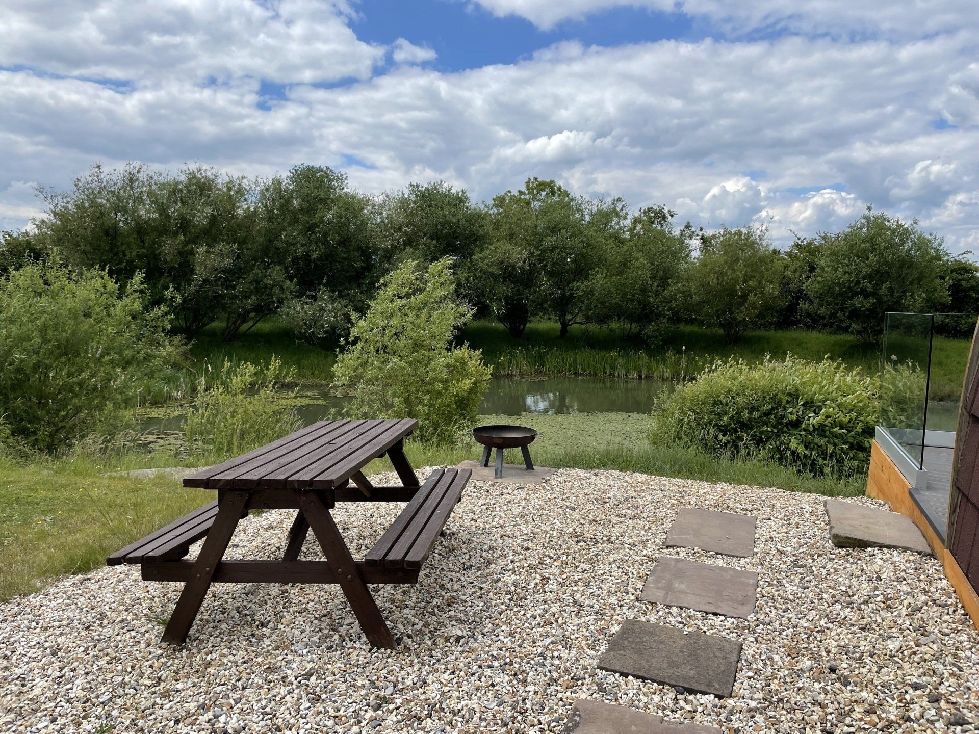 A picnic table is sitting on a gravel area next to a lake.