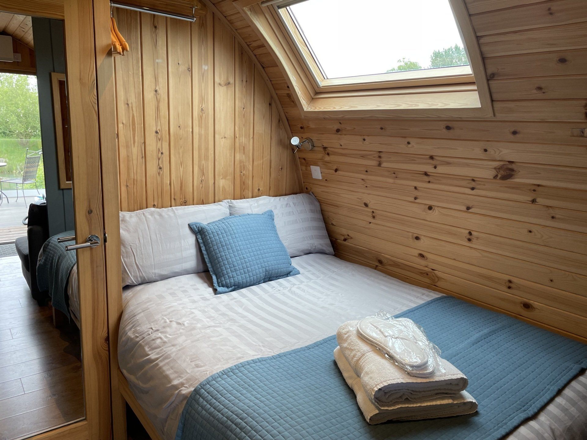 A bedroom with a bed and a window in the ceiling.