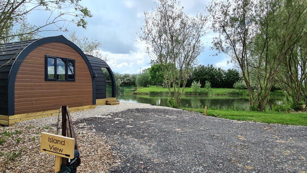 A small wooden house is sitting next to a lake.