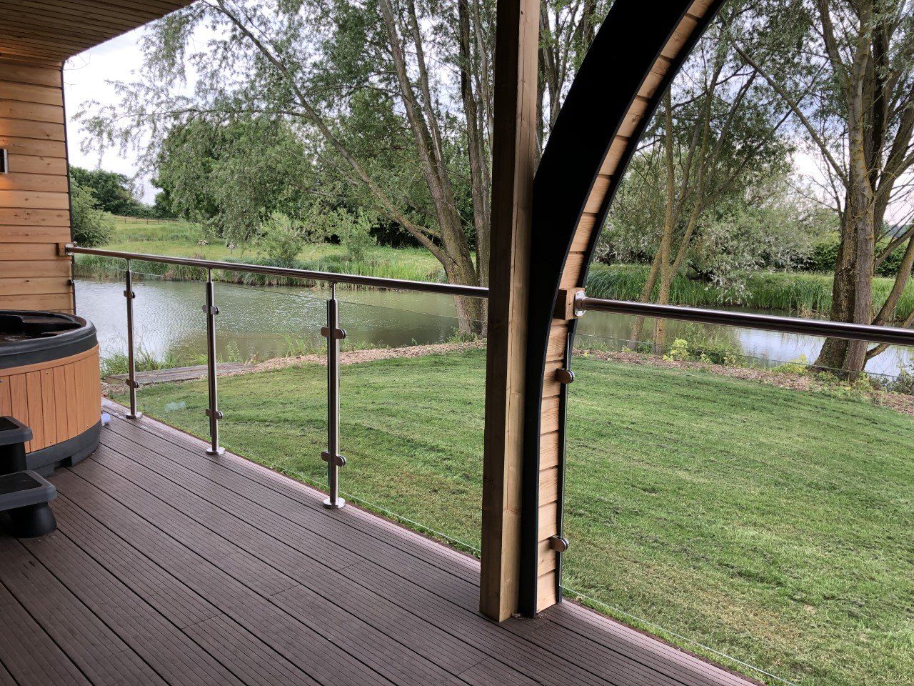 A deck with a hot tub and a view of a lake.